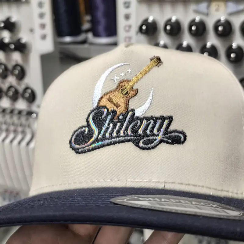 Gorra beige con logotipo bordado de una guitarra y una luna