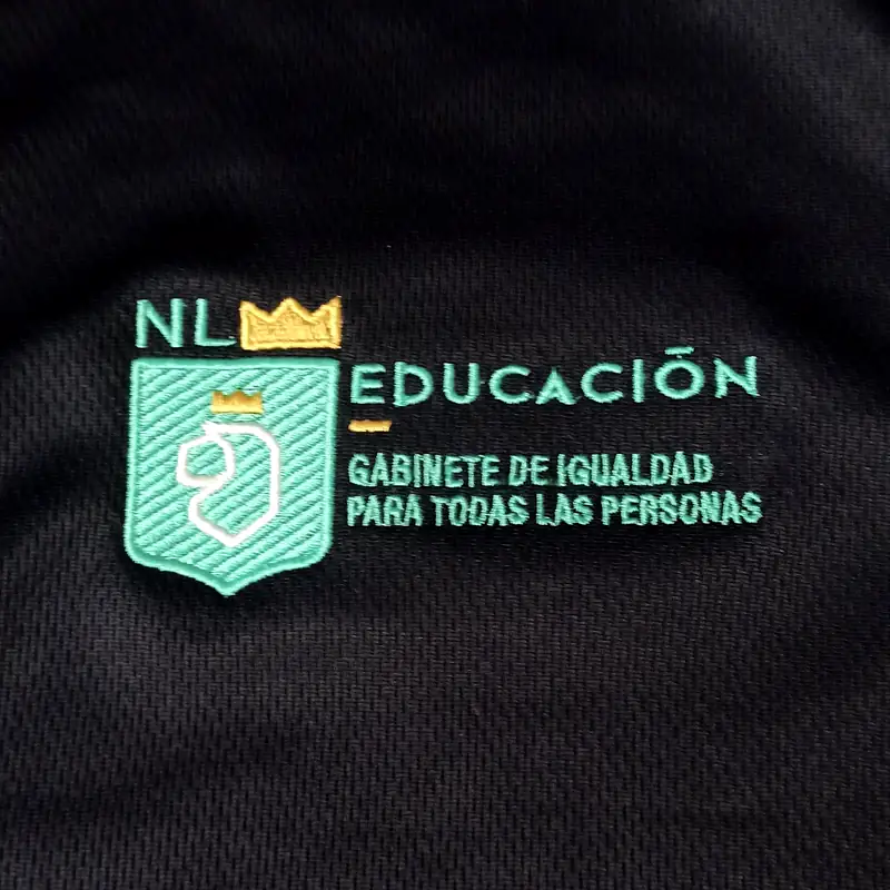 Escudo institucional bordado en verde y dorado sobre tela negra