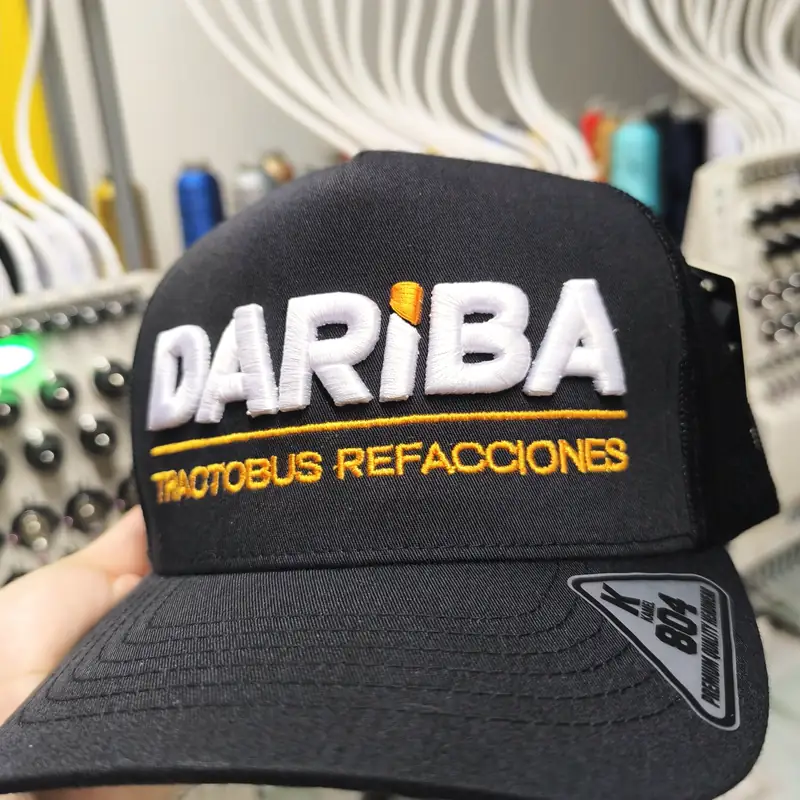 Gorra negra con letras bordadas en blanco y dorado